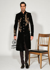 The Rich Black Sherwani jacket with a mandarin collar and jeweled shimmering gold zari embellishments on the front evokes regal elegance, reinterpreted with a modern twist.