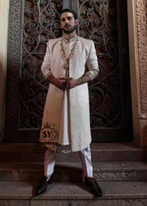 The Luminescence Ivory White Sherwani is a vision of refined romance, crafted in luminous karandi silk that seems to glow with elegance—hand embellishments on the collar and sleeves whispers of heritage artistry,