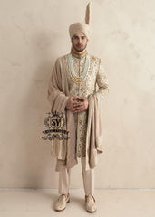 This sherwani is a masterpiece that blends timeless nobility with a modern sensibility. A finely hand-embroidered sherwani by Shazia Yasin, elevated with gold accents, paired with a statement mala, shawl and a bold turban for a timeless yet striking look.