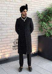 Embrace an aura of graceful distinction with our Elegant Black Sherwani, exquisitely complemented by a matching inner suit, Groom's necklace, and turban. This traditional wedding sherwani captures the very essence of refined elegance, seamlessly intertwining tradition with modern allure.