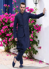 A stylish waistcoat crafted from luxurious navy blue raw silk fabric. The waistcoat itself, the front, and the sleeves are adorned with intricate threadwork and embroidery, giving it a refined and traditional feel.
