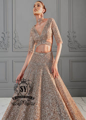The essence of romance reimagined into a showstopping Lehenga silhouette. This bridal dress features a sculpted choli bodice with a dramatic front waist and daring sheer side cutouts, creating an interplay of strength and sensuality.