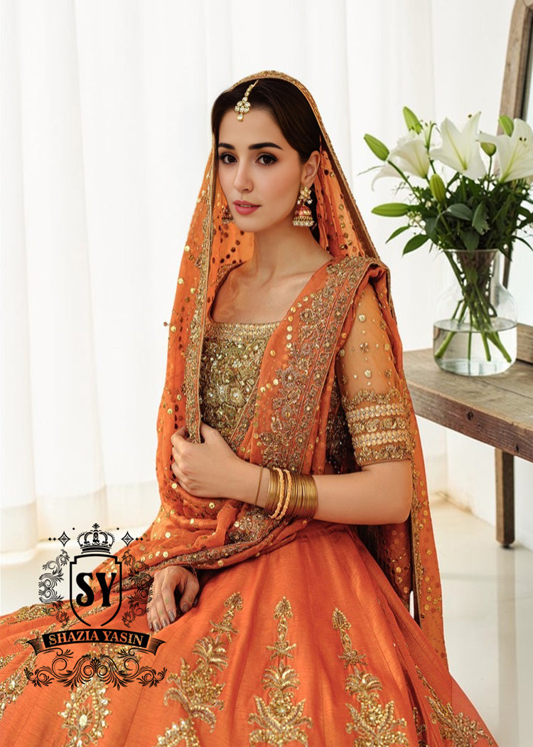 A stunning ensemble featuring Persimmon net blouse and an intricately embroidered Raw silk lehenga in the same vibrant hue. A shimmering kaamdani dupatta adds charm and sophistication to the ensemble.
