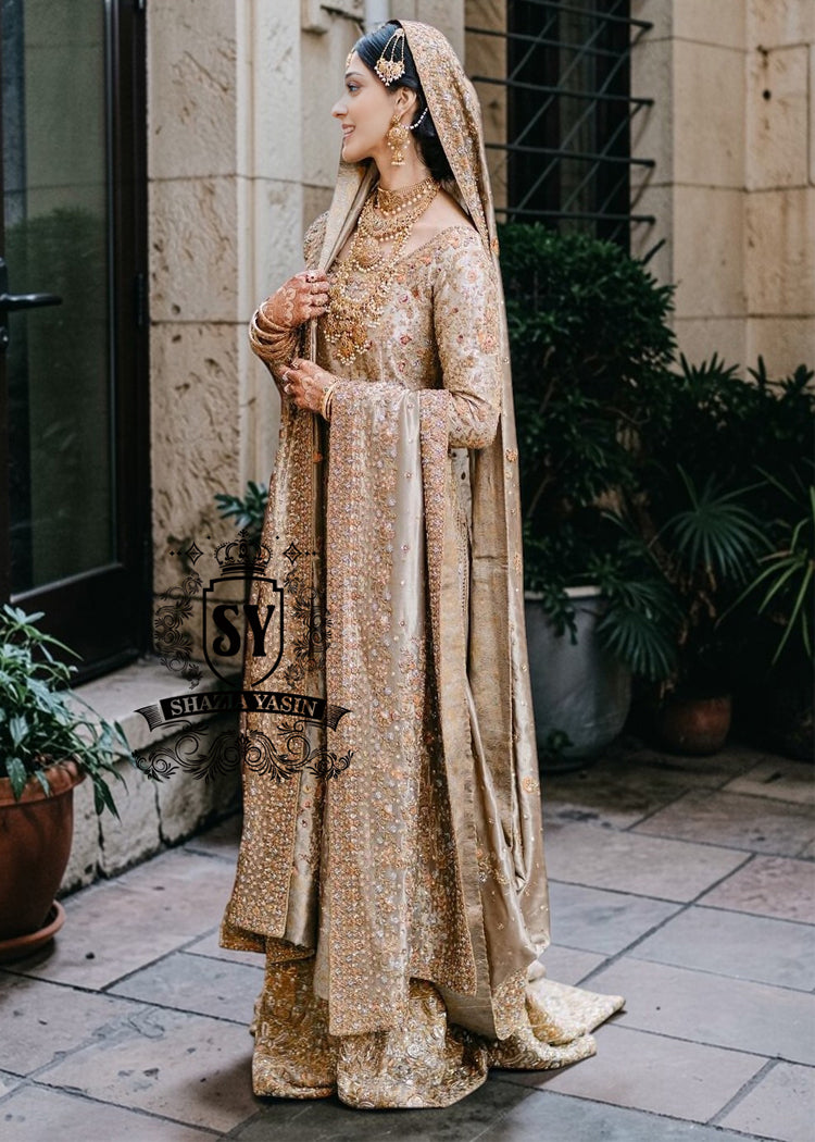 A majestic wedding dress made of luxurious Lame fabric in a lush farshi lehenga silhouette that radiates elegance. Long shirt creates an exquisite effect. The decor in the form of delicate flourishing embellishments adds romance.