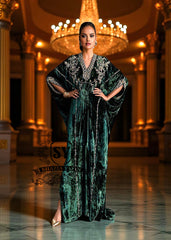 Woman in a green evening Kaftan standing in an opulent room with a chandelier