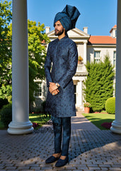 Man in a blue traditional outfit with a matching turban standing in front of a classical building.
