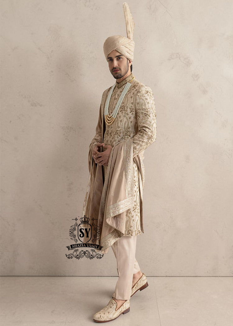 This sherwani is a masterpiece that blends timeless nobility with a modern sensibility. A finely hand-embroidered sherwani by Shazia Yasin, elevated with gold accents, paired with a statement mala, shawl and a bold turban for a timeless yet striking look.