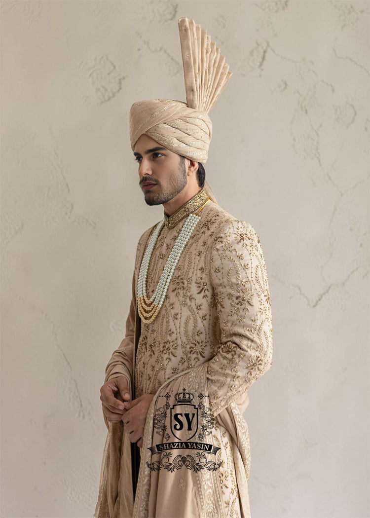 This sherwani is a masterpiece that blends timeless nobility with a modern sensibility. A finely hand-embroidered sherwani by Shazia Yasin, elevated with gold accents, paired with a statement mala, shawl and a bold turban for a timeless yet striking look.
