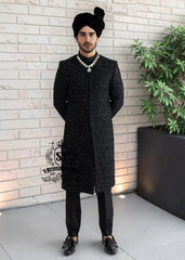 Embrace an aura of graceful distinction with our Elegant Black Sherwani, exquisitely complemented by a matching inner suit, Groom's necklace, and turban. This traditional wedding sherwani captures the very essence of refined elegance, seamlessly intertwining tradition with modern allure.