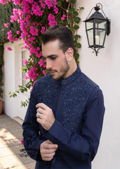 A stylish waistcoat crafted from luxurious navy blue raw silk fabric. The waistcoat itself, the front, and the sleeves are adorned with intricate threadwork and embroidery, giving it a refined and traditional feel.